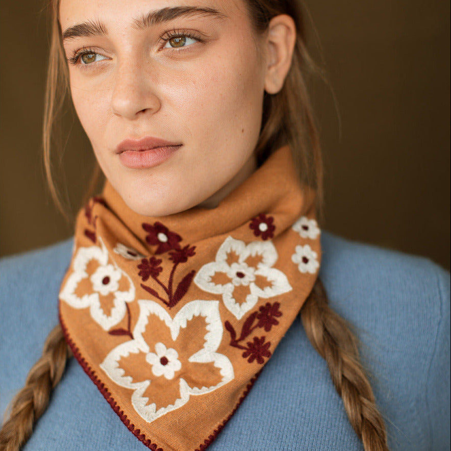 Woman wearing a brown floral-patterned scarf with a blurred background